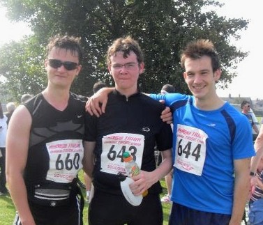 Three young men in triathlon race numbers, arms round each other, grinning after the 2008 race