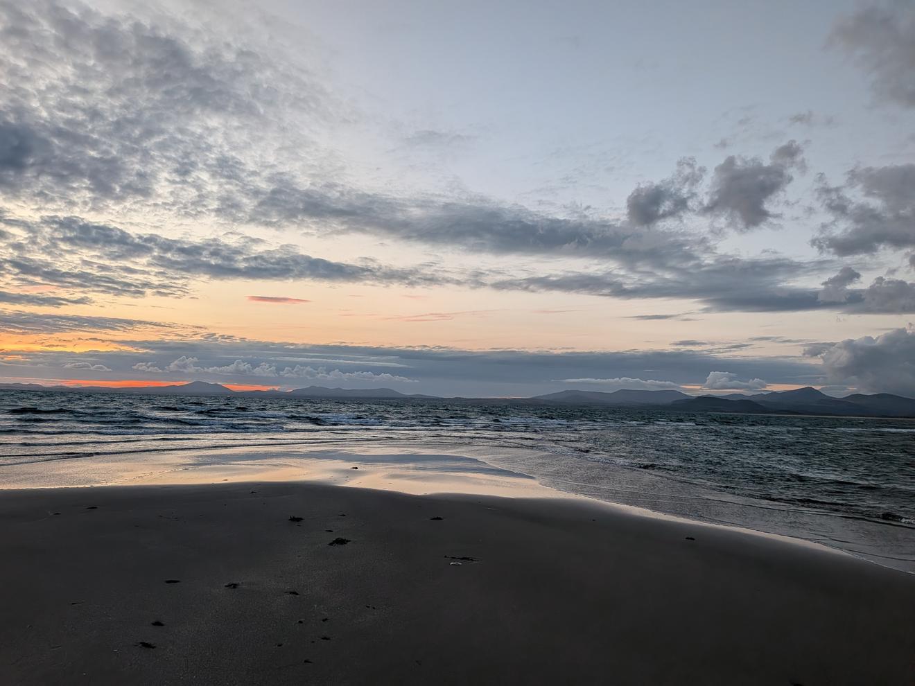 The same Shell Island beach at sunset, tide out, the mountains of the Llyn Peninsula on the horizon