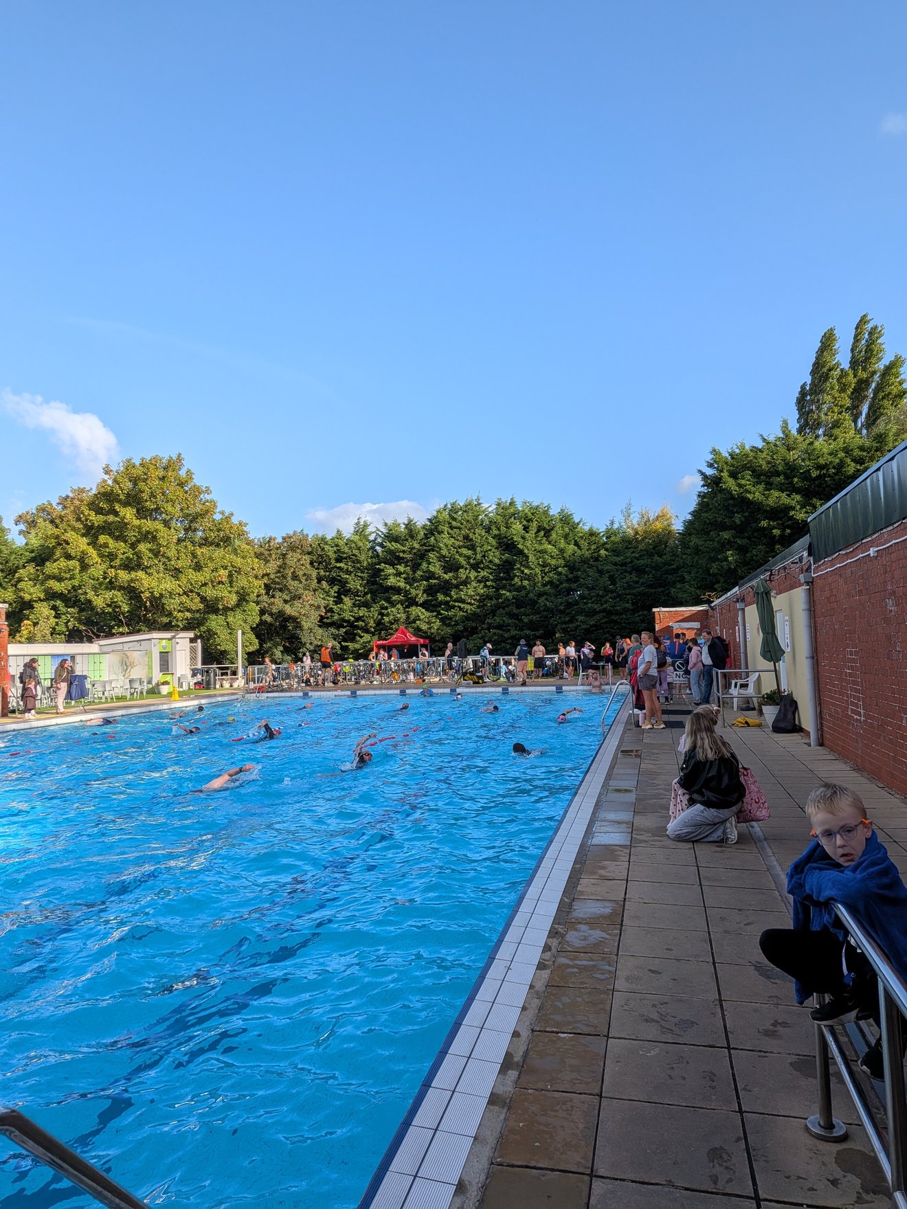 Outdoor pool full of swimmers on race morning, bikes racked in the background